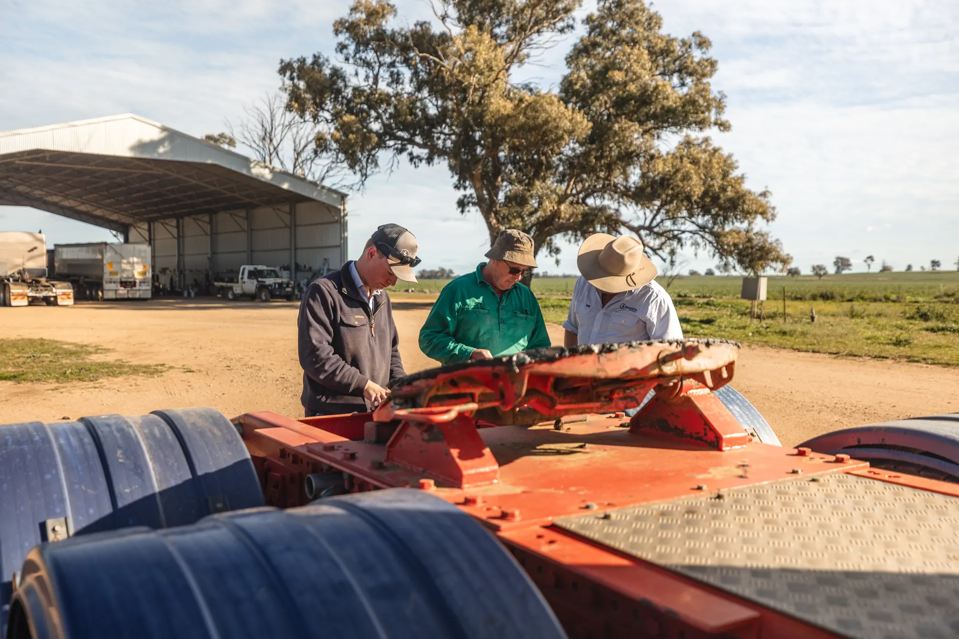 A Benabilla agent reviews sale paperwork with a seller beside a red trailer